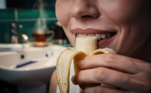 Illustration of a person gently rubbing the inner side of a banana peel on their teeth as an enzymatic polish to brighten their smile